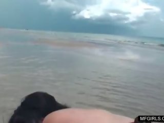 Nydelig brunette tenåring i bikini erting på den strand